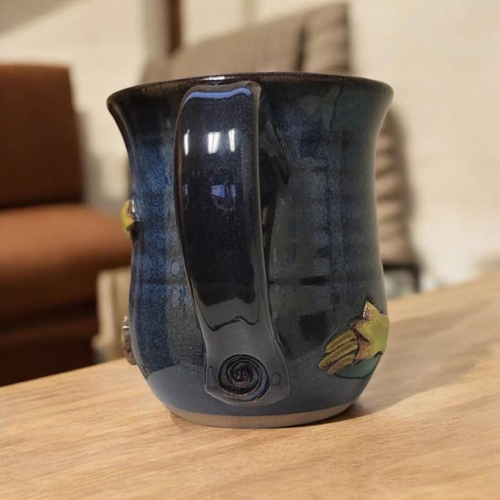 Dark blue ceramic mug with a decorative handle on a wooden surface