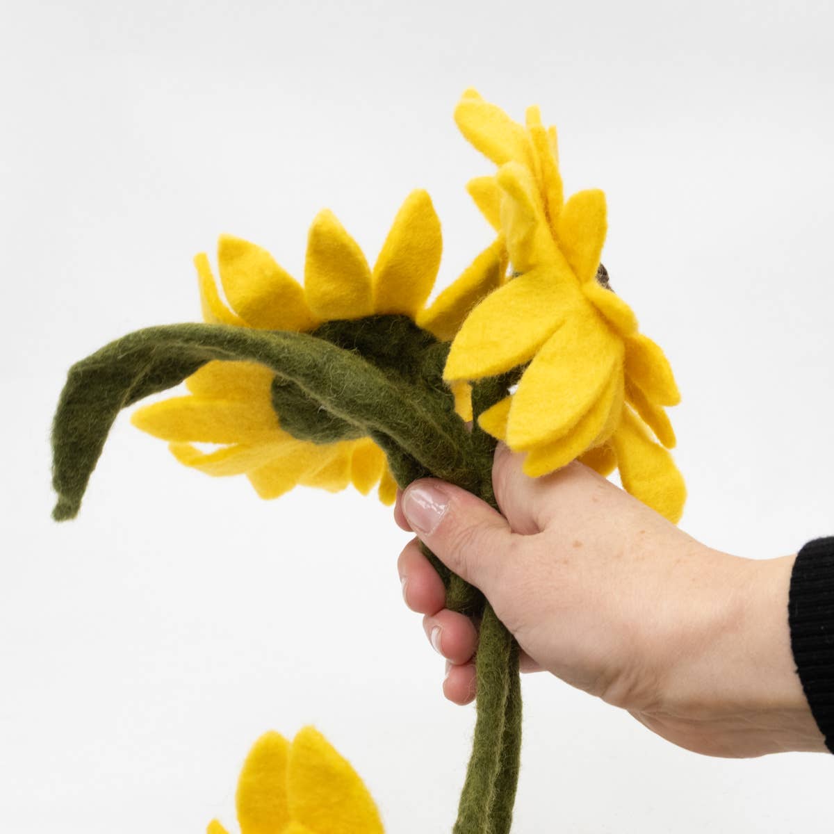 Hand holding a felt sunflower garland against a white background