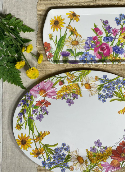 Two floral-patterned trays on a textured surface with greenery.