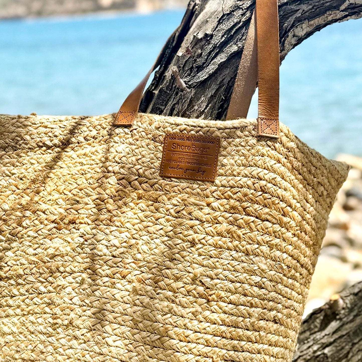 Woven straw bag with leather straps against a blurred natural background