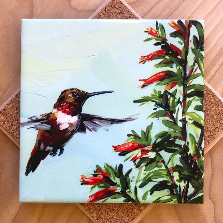 Trivet with a hummingbird and flowers design on a wooden background.