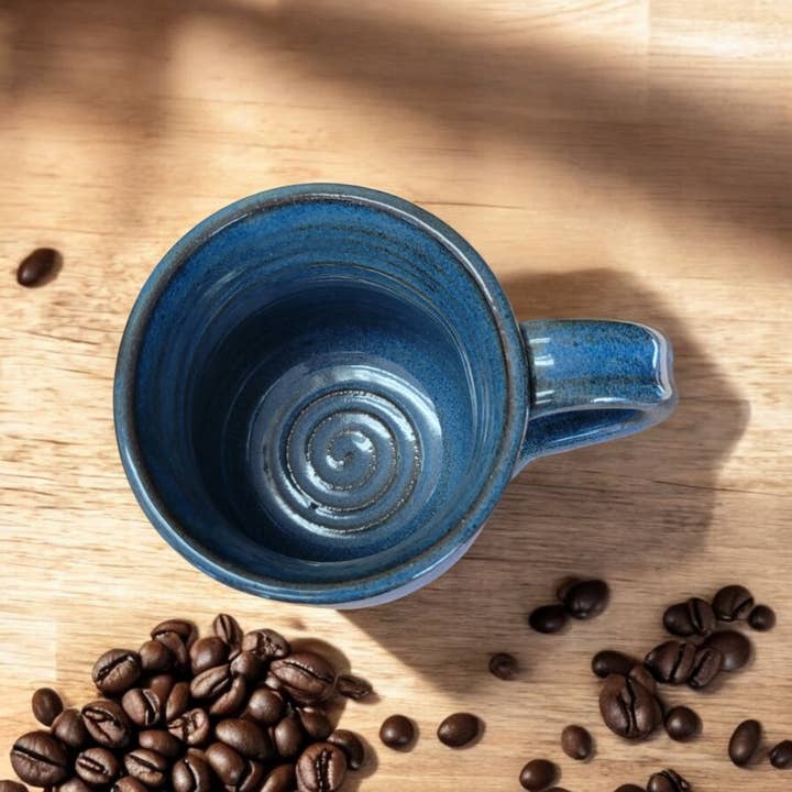 Blue ceramic mug on a wooden surface with coffee beans around it
