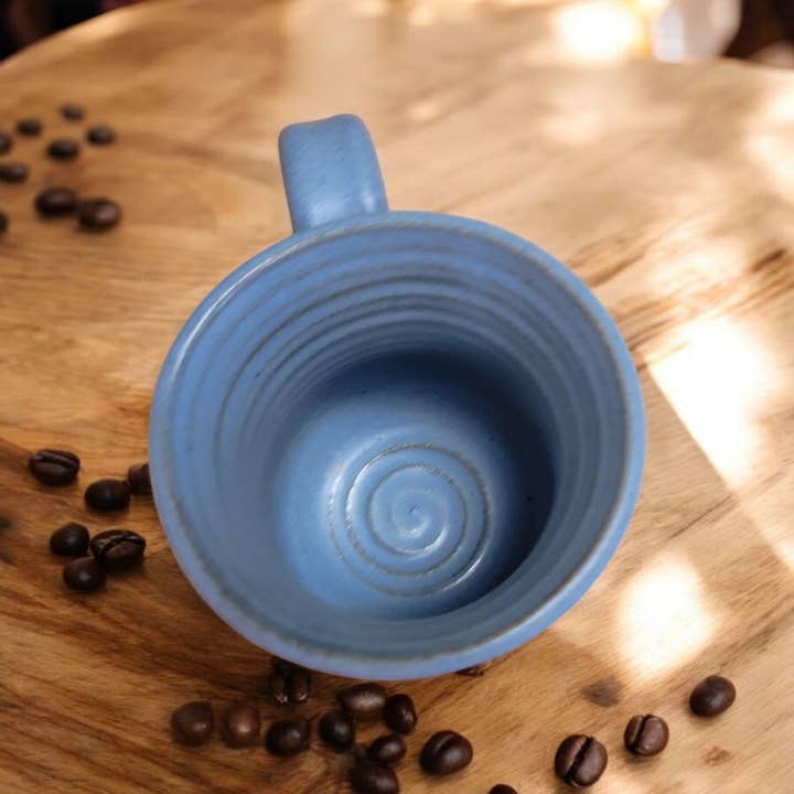 Blue ceramic mug on a wooden surface with coffee beans around it