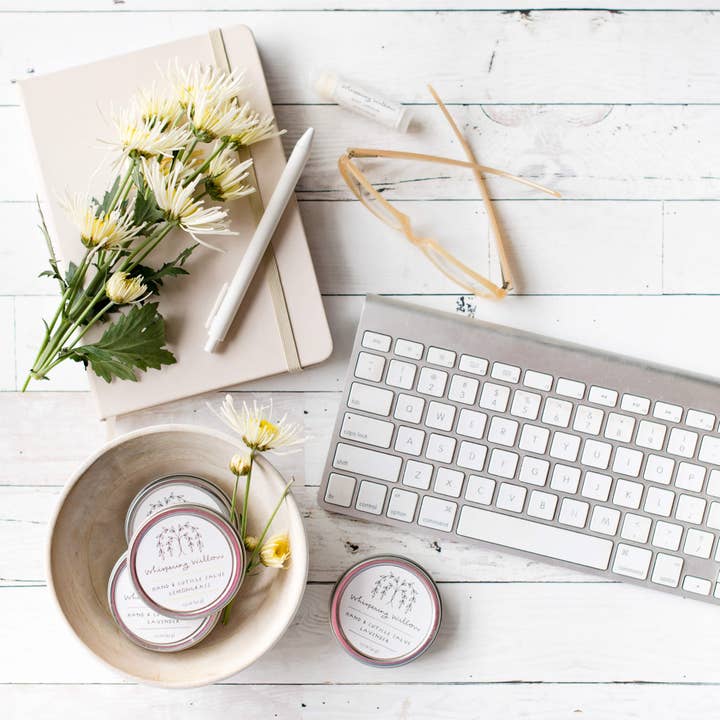 Keyboard, flowers, and small containers on a white wooden surface