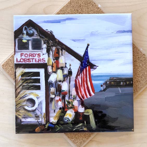 Trivet with a design of a lobster shop and American flag on a wooden surface