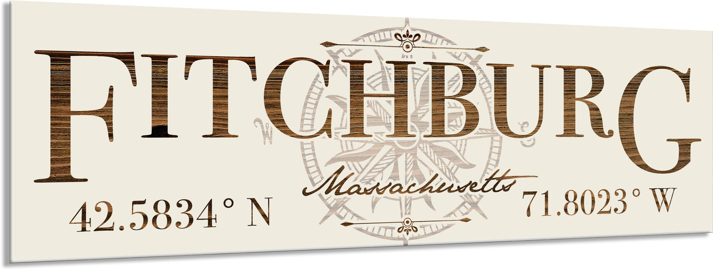 Decorative sign with 'Fitchburg, Massachusetts' text and coordinates on a beige background