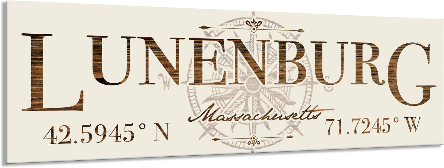 Decorative sign with 'Lunenburg, Massachusetts' text and coordinates on a beige background