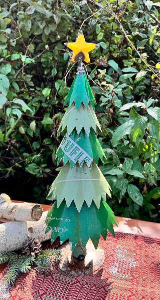 Green metal Christmas tree with a star on top against a natural background