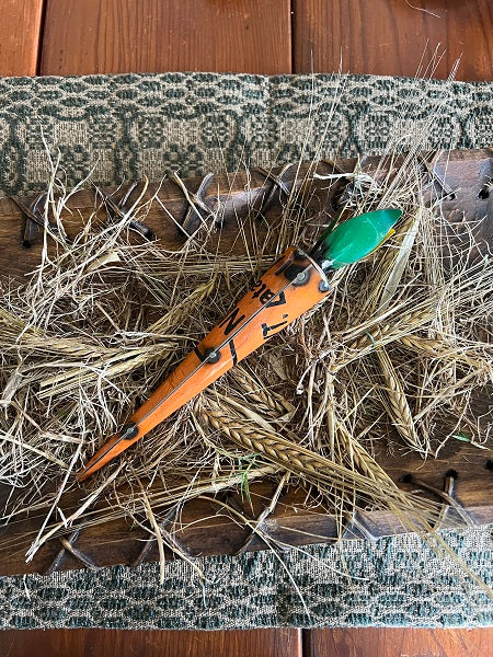 Metal carrot sculpture with a green stem on a textured surface