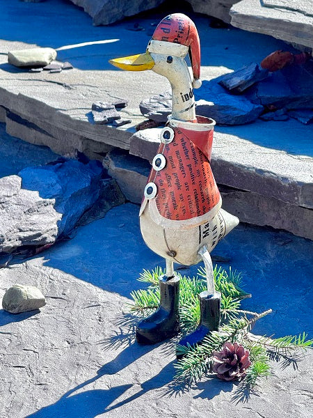 Decorative duck sculpture made from metal on a rocky surface.
