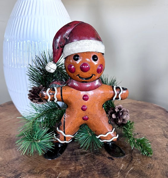 Decorative gingerbread man figurine with a Santa hat on a wooden surface.