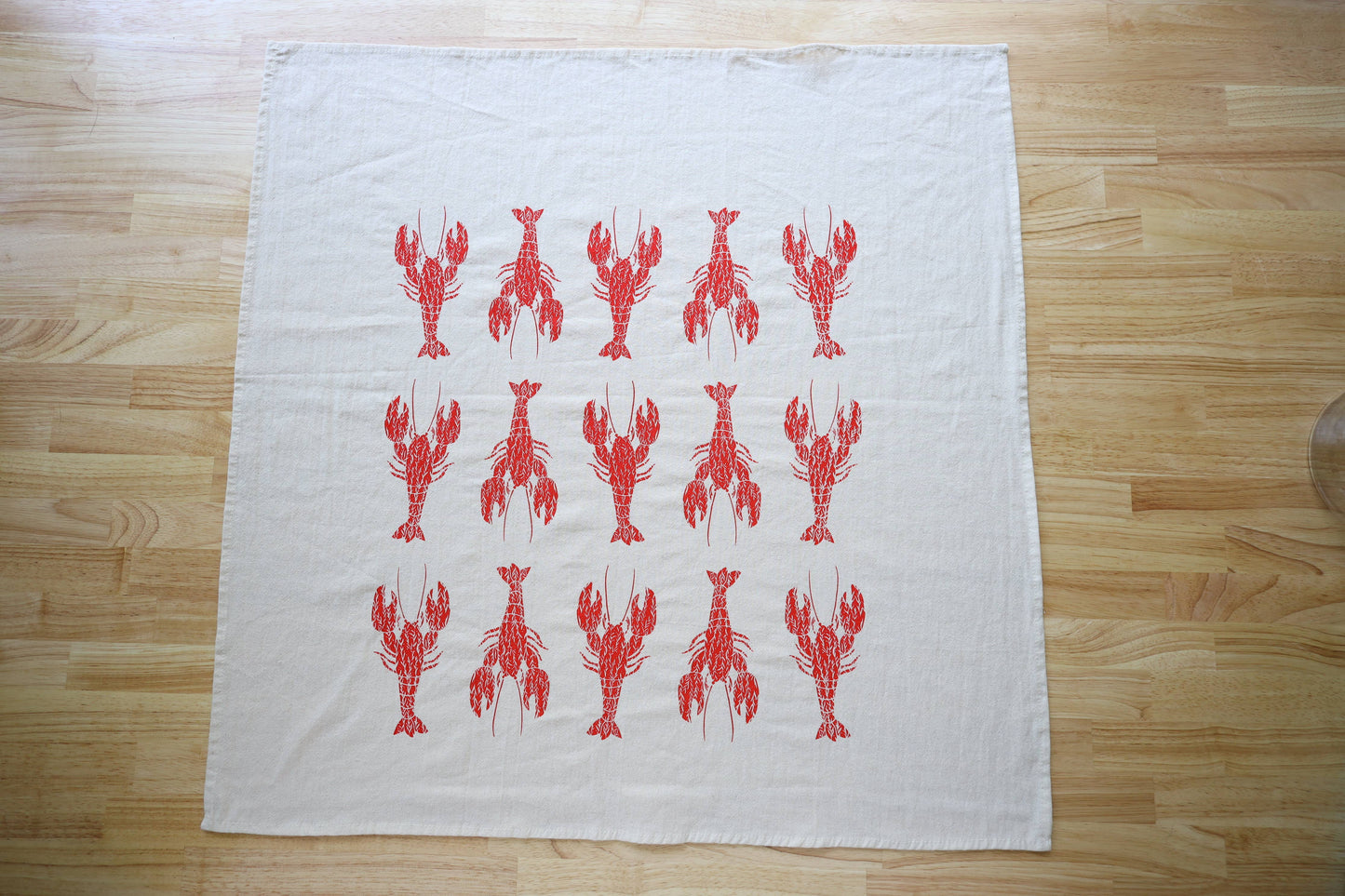 White towel with red lobster pattern on a wooden surface