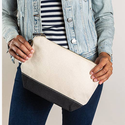 Person holding a beige clutch bag with black accents
