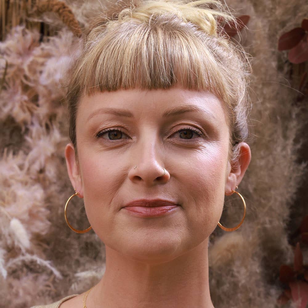 Woman with styled hair and hoop earrings against a floral background