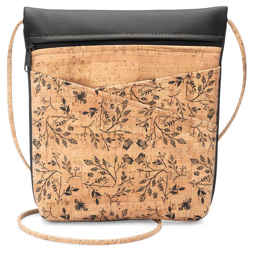 A crossbody bag with a black faux leather top and a floral cork patterned bottom with an adjustable strap.