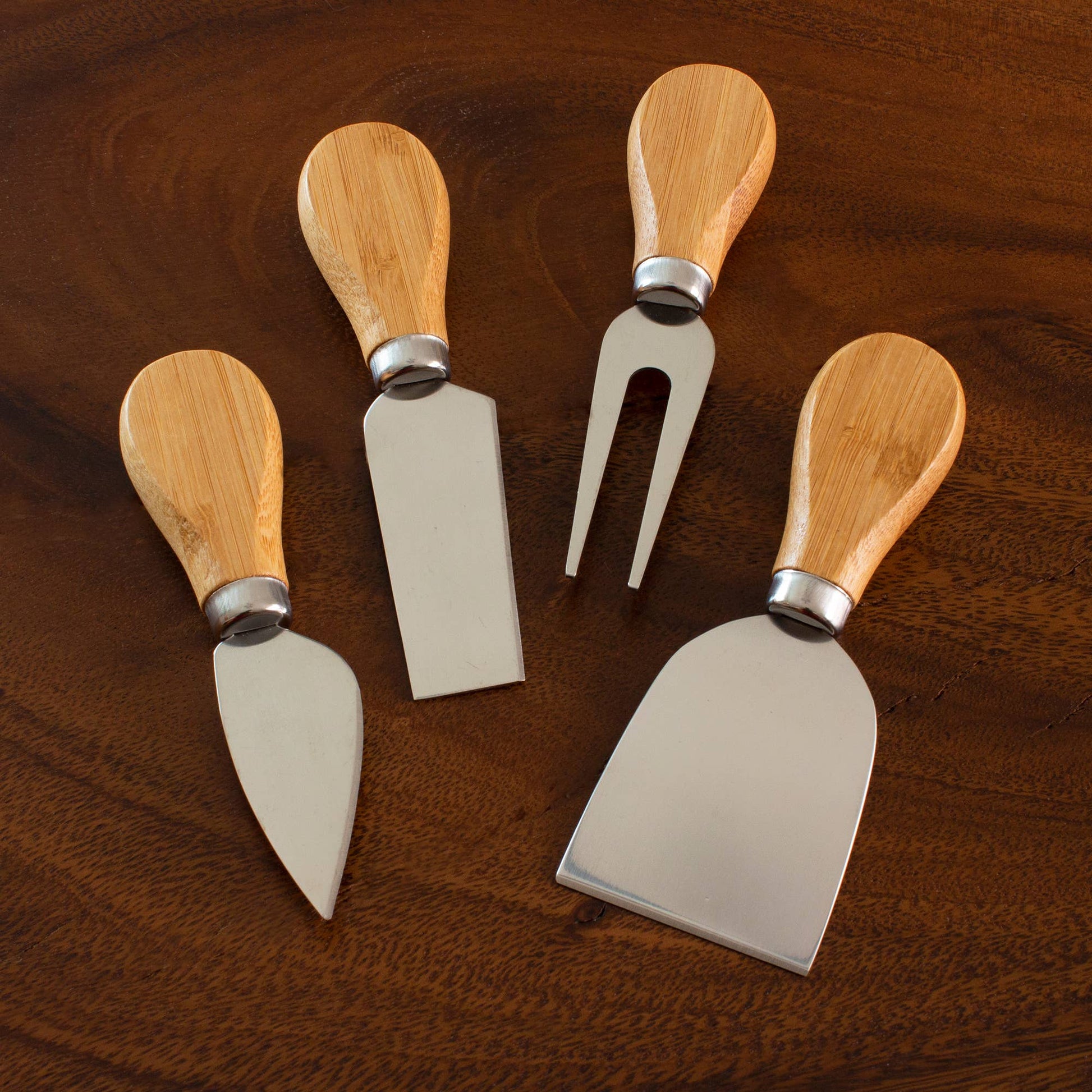Set of four wooden-handled cheese tools on a wooden surface