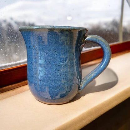 Blue ceramic mug on a windowsill with a snowy outdoor view