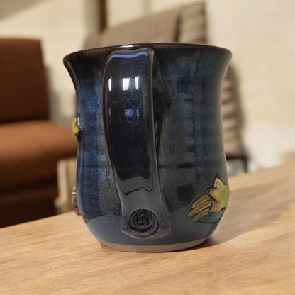 Dark blue ceramic mug with a decorative handle on a wooden surface