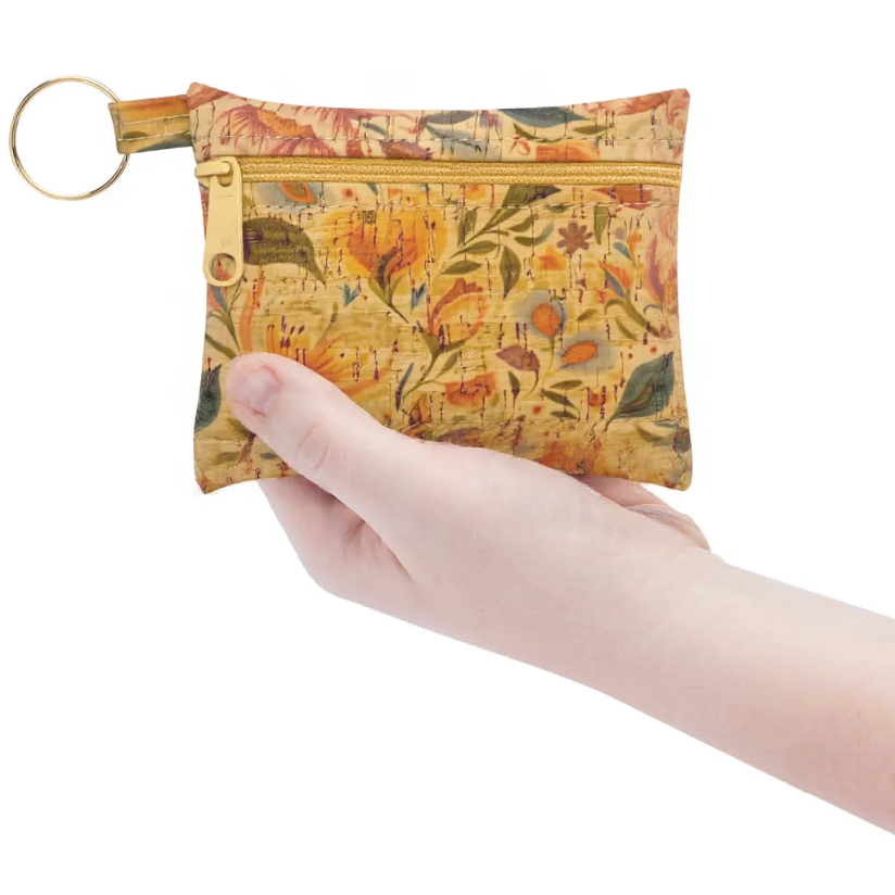 Hand holding a floral-patterned pouch with a key ring on a white background
