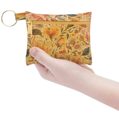 Hand holding a floral-patterned pouch with a key ring on a white background