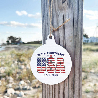 Round white ornament with American flag design and text hanging on a wooden board outside