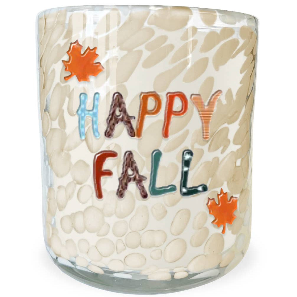 A clear glass candle jar with a textured, pebble-like pattern in cream and beige, featuring the words 'HAPPY FALL' in multicolored letters and two orange maple leaf graphics on the front.