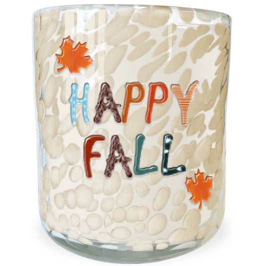 A clear glass candle jar with a textured, pebble-like pattern in cream and beige, featuring the words 'HAPPY FALL' in multicolored letters and two orange maple leaf graphics on the front.