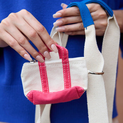 Person holding a small white bag with pink accents against a blue background