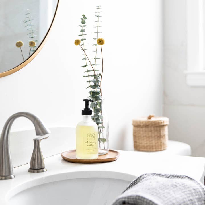 Bathroom counter with a bottle of soap, mirror, and towel