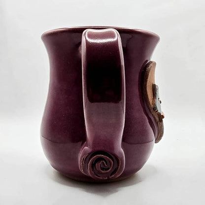 Purple ceramic mug with handle and decorative element on a white background