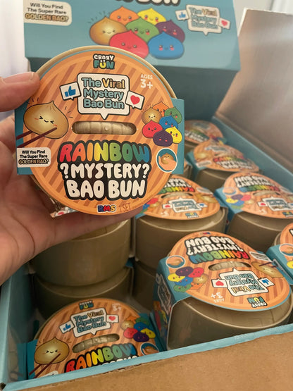 Hand holding a 'Rainbow Mystery Bao Bun' packaging with more packages in the background.