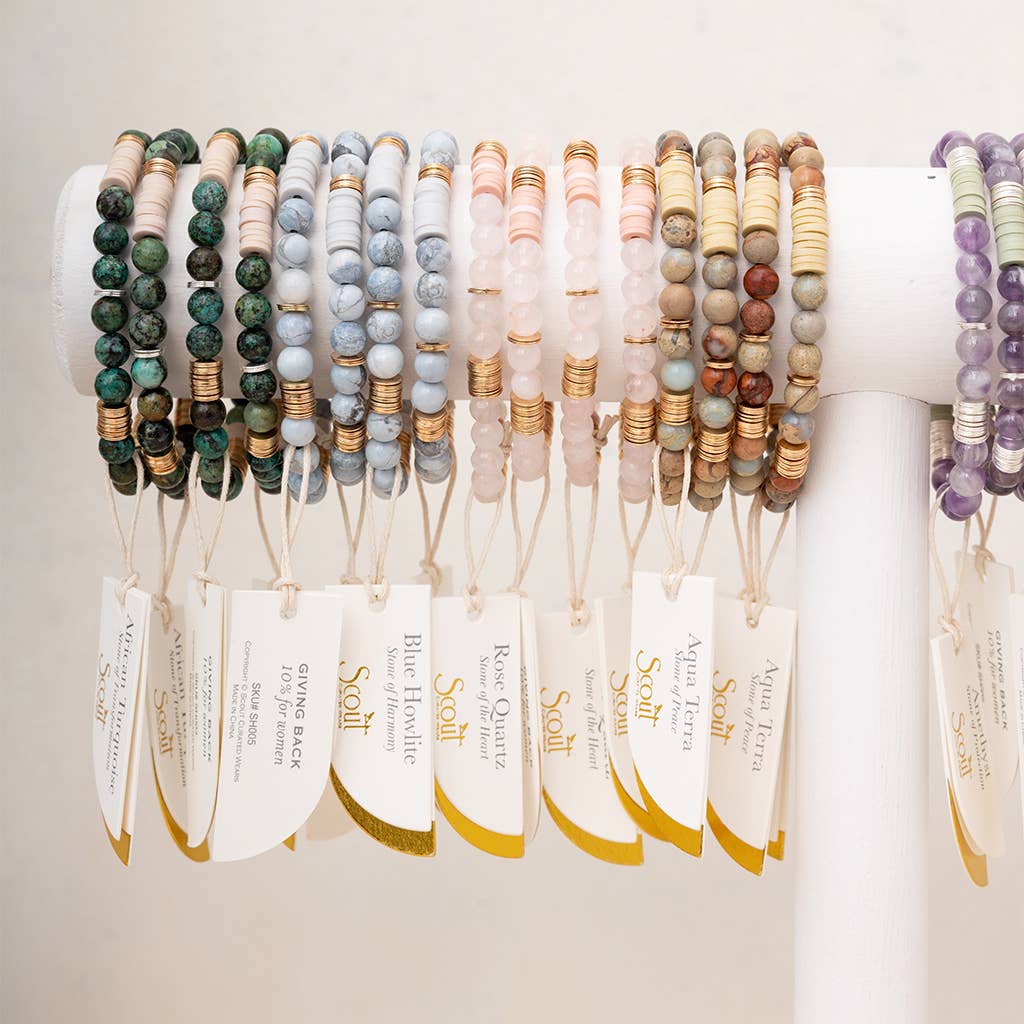 Row of beaded bracelets on a white surface with tags indicating material types.