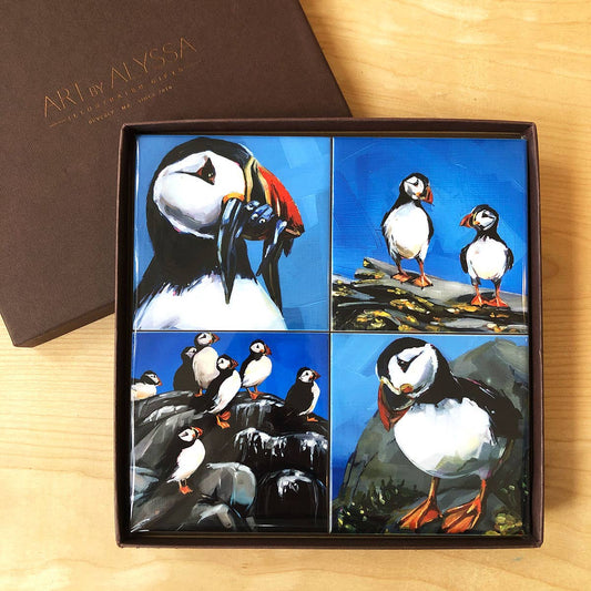 Box of ceramic coasters with puffin designs on a wooden surface