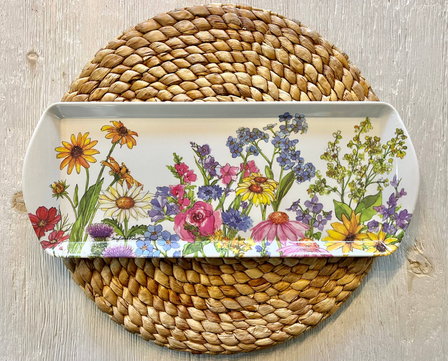 Decorative tray with floral design on a woven mat
