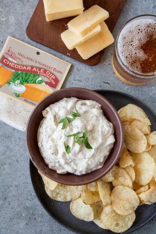 Bowl of dip with chips and a glass of beer on a gray surface