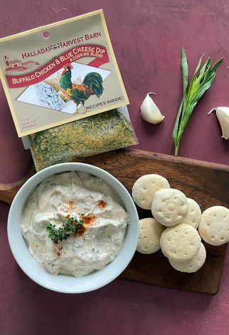 Buffalo chicken and blue cheese dip with crackers and herbs on a wooden board