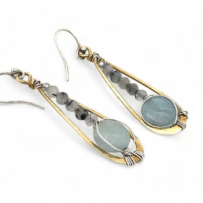 Pair of earrings with gold and silver accents and green stones on a white background