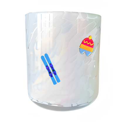 Glass candle with winter-themed designs of skis and a colorful hat on a white background