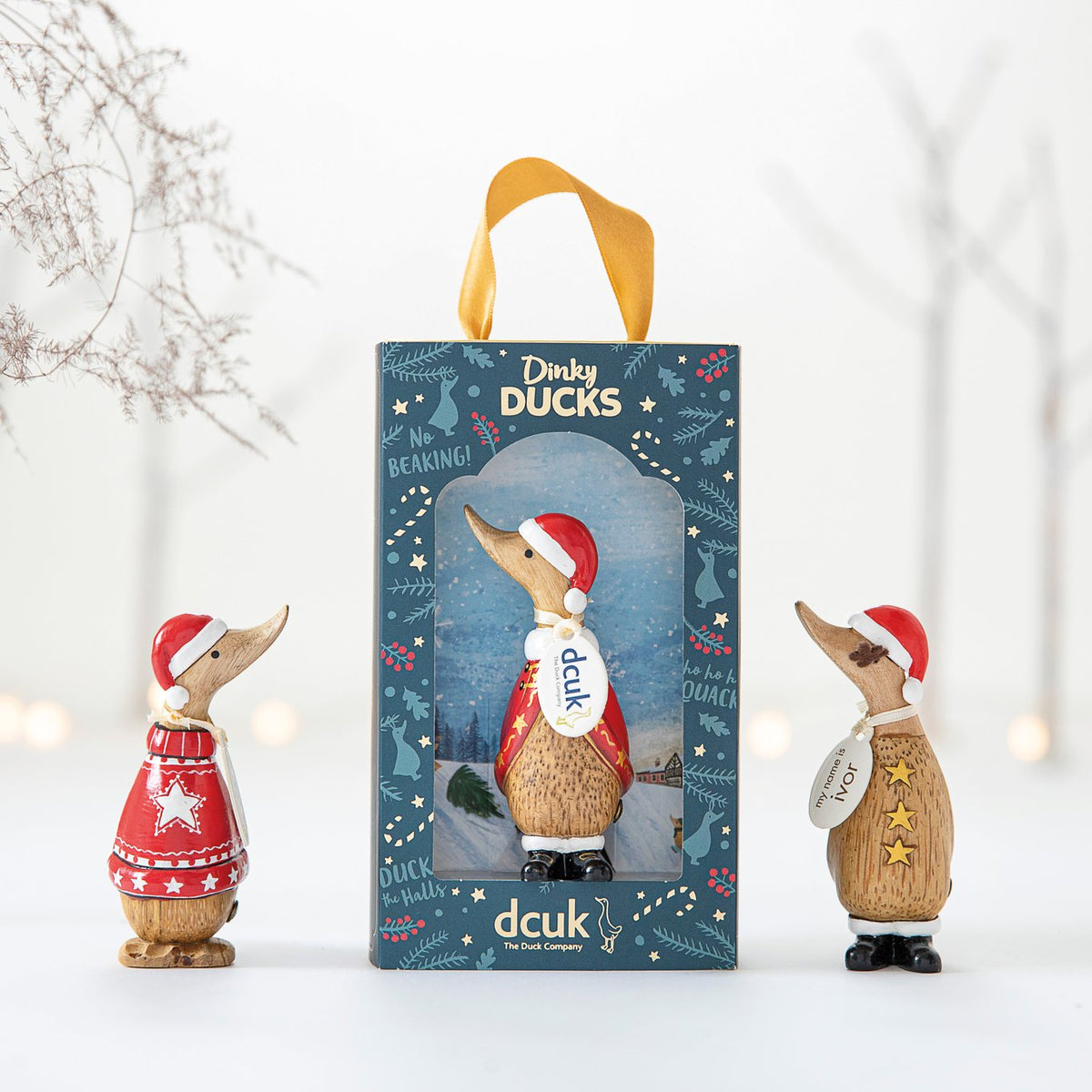 Decorative duck figurine with a Santa hat in front of its packaging on a white background