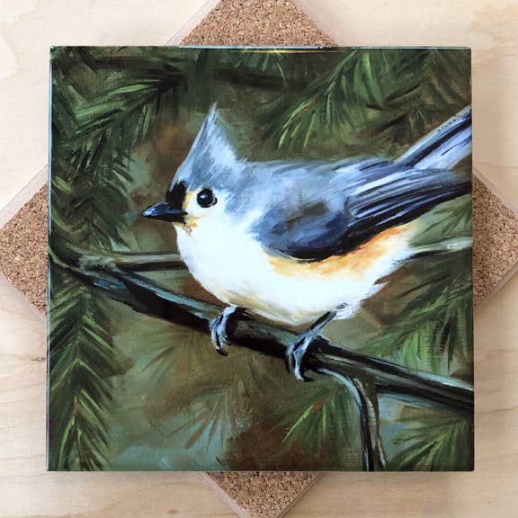 Trivet with a painting of a bird perched on a branch with a natural background.
