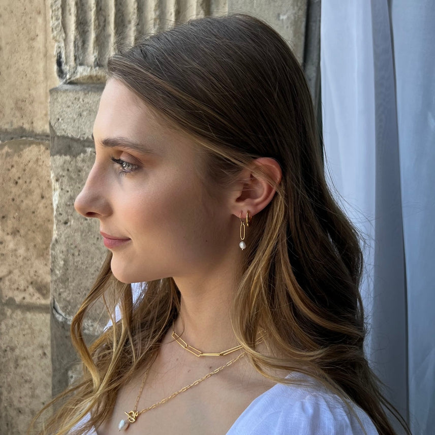 Woman wearing gold jewelry against a stone wall background