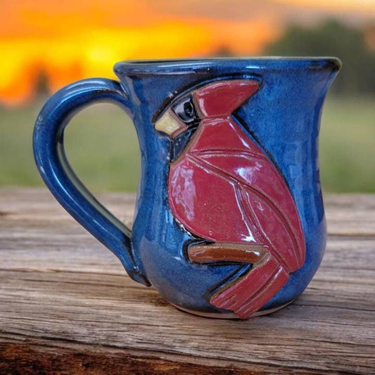 Ceramic mug with a red cardinal design on a wooden surface