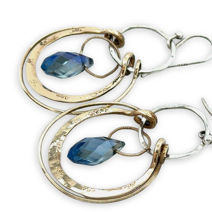 Pair of hoop earrings with blue gemstones on a white background