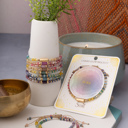 Colorful bracelets on a vase with a candle and packaging in the background