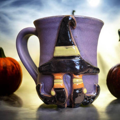 Ceramic mug with a witch hat and boots design on a Halloween-themed background. All images associated with this product listing show the same mug from various angles. The design is only on one side of the mug.