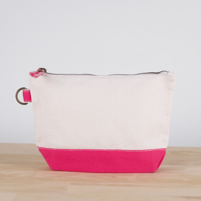 White and pink pouch on a wooden surface with a light gray background