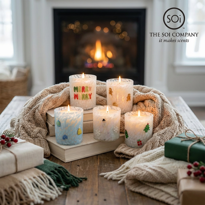 Candles with festive designs on a wooden tray in front of a fireplace, featuring the Soi Company logo.