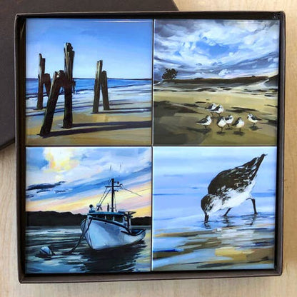 Set of four ceramic coasters with beach-themed artwork in a gift box.