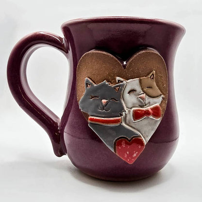 Purple mug with two cats in a heart design on a white background