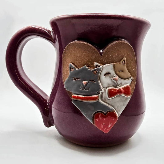 Purple mug with two cats in a heart design on a white background
